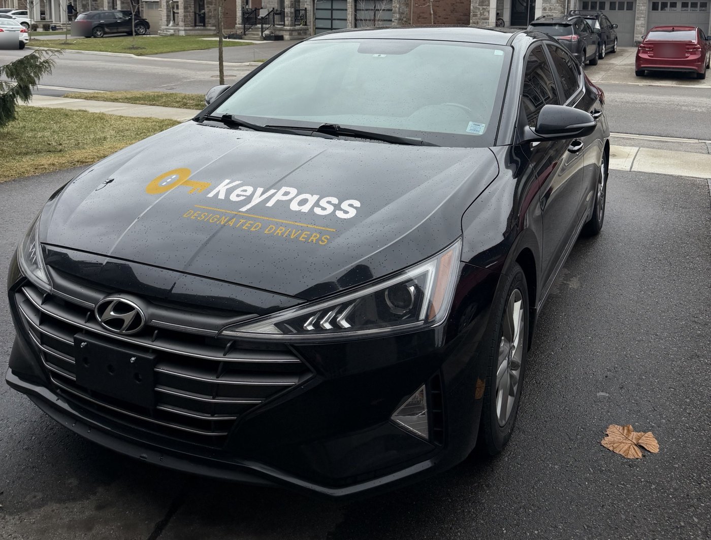 The black KeyPass car with the gold KeyPass logo on the hood, parked in a driveway